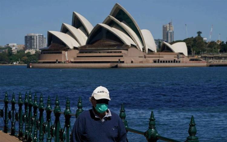 Seorang warga berjalan di tepi pelabuhan di seberang Sydney Opera House selama penguncian COVID-19 di Sydney, Australia, Rabu (6/10/2021). (ANTARA/Reuters/as)