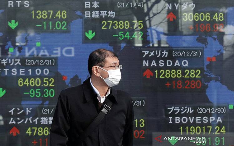 Pejalan kaki melintas di depan layar elektronik pergerakan Indeks Nikkei di Bursa Efek Tokyo, Jepang. ANTARA/REUTERS/Kim Kyung-Hoon/am.