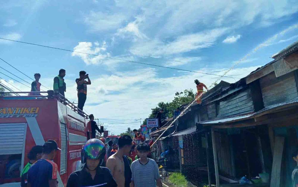 Tim Damkar Kota Palangka Raya dibantu pihak kepolisian maupun relawan berupaya memadamkan api