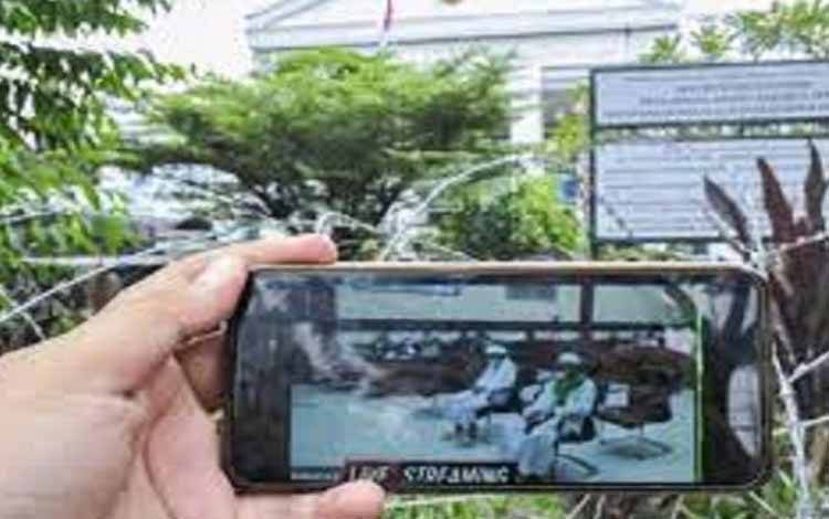 Jurnalis mengamati layar telefon pintar sidang Rizieq Shihab yang beragendakan tuntutan dari Jaksa Penuntut Umum (JPU) di Pengadilan Negeri Jakarta Timur, Kamis (3/6/2021)