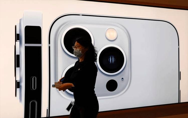 Foto Dokumen: Seorang karyawan Apple yang mengenakan masker wajah berjalan melewati gambar iPhone 13 Pro di Apple Store pada hari peluncuran seri Apple iPhone 13 baru, di Beijing, China, 24 September 2021. ANTARA/REUTERS/Carlos Garcia Rawlins/Foto Dokumen