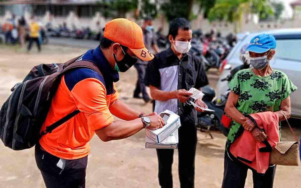 Petugas BPBD Damkar Barito Timur membagikan masker kepada peserta vaksinasi.