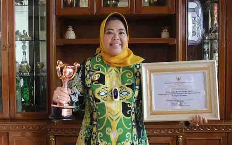 Bupati Kobar Nurhidayah memegang penghargaan APE dari kementerian PPA