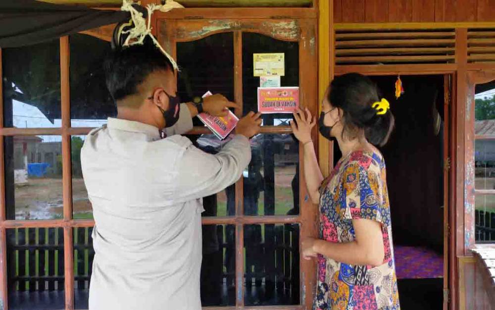 Foto : Personel Polsek Aru Utara pasang stiker pada rumah warga yang sudah vaksin di Kelurahan Pangkut.