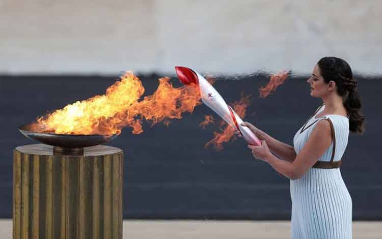 Aktris Yunani Xanthi Georgiou, memainkan peran Pendeta Tinggi menyalakan obor dengan api selama upacara serah terima di Athena untuk Olimpiade Musim Dingin Beijing 2022, Stadion Panathenaic, Athena, Yunani, Selasa (19/10/2021). ANTARA FOTO/REUTERS/Louiza Vradi/FOC/sa. (REUTERS/LOUIZA VRADI)