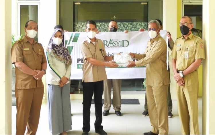 Mewakili Abdul Rasyid Foundation, Kharis Nuryanto menyerahkan bantuan pakaian seragam bagi vaksinator covid-19 yang diterima Sekda Kobar Suyanto, Kamis, 21 Oktober 2021.