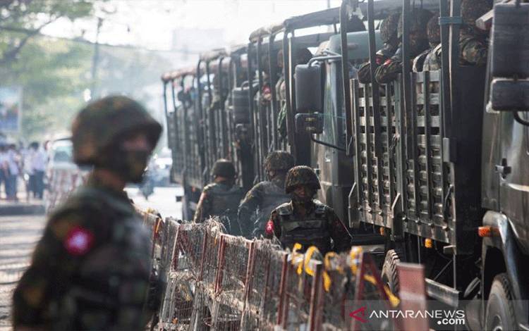 Arsip - Tentara berdiri di samping kendaraan militer ketika orang-orang berkumpul untuk memprotes kudeta militer di Yangon, Myanmar, 15 Februari 2021. (REUTERS/Stringer.)