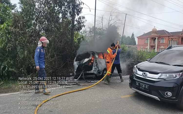 Anggota pemadam kebakaran memadamkan mobil terbakar