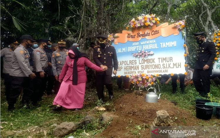 Kepala Polres Lombok Timur, AKBP Herman Suriyono, didampingi istri ketika mengikuti upacara pemakaman jenazah Brigadir Polisi Satu HT, di Gontoran Timur, Lombok Barat, NTB, Selasa (26/10/2021). ANTARA/Dhimas BP