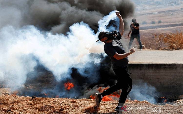 Arsip - Warga Palestina mengembalikan tabung gas air mata yang ditembakkan pasukan Israel dalam aksi protes menentang permukiman Israel di Beit Dajan, Tepi Barat yang diduduki Israel, Jumat (22/10/2021). (ANTARA/Reuters)