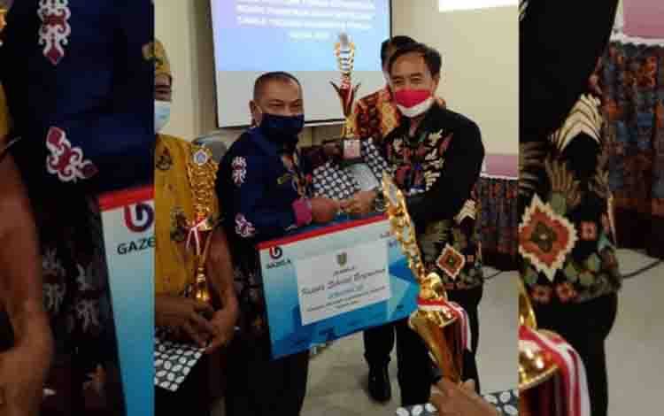 Kepala SDN 2 Sawahan, Jadi, menerima penghargaan dari Kepala Dinas Pendidikan Kalimantan Tengah, Ahmad Syaifudi. 