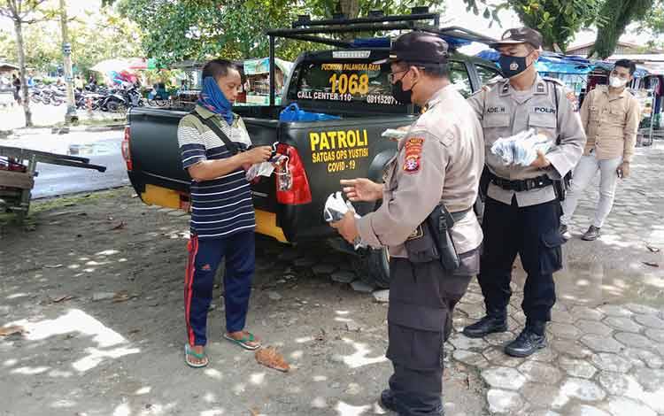 Anggota Polresta Palangka Raya membagikan masker untuk warga di kawasan Pasar Kahayan.