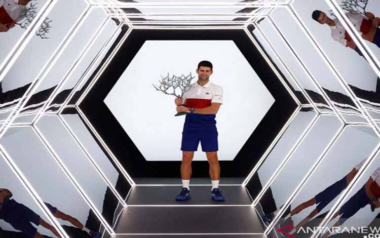 Novak Djokovic membawa piala dan melakukan selebrasi setelah memenangi final Paris Masters melawan petenis Rusia Daniil Medvedev di Accor Arena, Paris, Prancis, Minggu (7/11/2021)