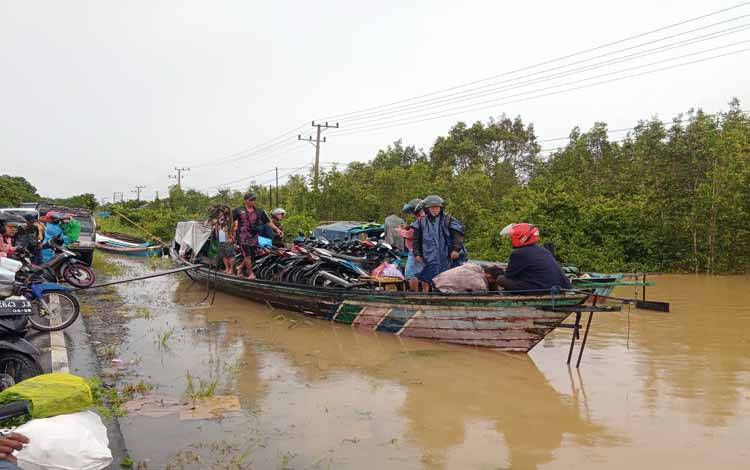 Warga menggunakan jasa angkutan perahu kelotok menyeberangi banjir di Desa Tanjung Sangalang, Kecamatan Kahayan Tengah, Kabupaten Pulang Pisau
