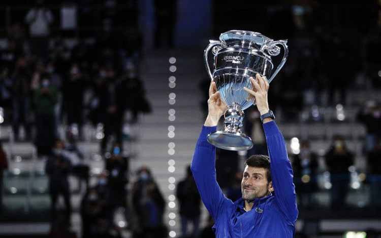 Petenis Serbia Novak Djokovic berpose mengangkat trofi untuk selebrasi pencapaiannya menjadi petenis nomor 1 dunia ATP akhir tahun usai memenangi pertandingan babak penyisihan grup ATP Finals melawan Casper Ruud dari Norwegia di Turin, Italia, Senin (15/11/2021)