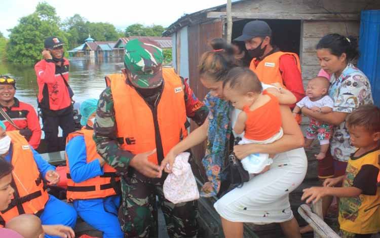 Babinsa Koramil 1016-01 Pahandut, Pelda Nurkholis bersama petugas kesehatan dan lainnya saat mengevakuasi ibu dan balita terdampak banjir di Petuk Katimpun, Selasa 16 November 2021
