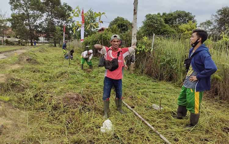 DLH Sukamara bersama LPMK Pandang saat membersihkan rumput di lapangan sepak bola Padang Betuah.