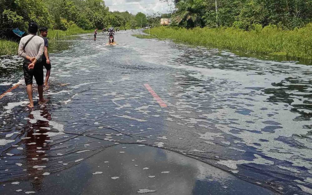 Air menggenangi jalan di Desa Pilang, Kecamatan Jabiren Raya, Kabupaten Pulang Pisau. Warga sekitar sudah mempersiapkan jasa angkutan perahu klotok untuk menyeberangi banjir, 23 November 2021.