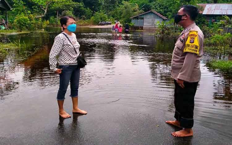 Anggota Polsek Bukit Batu berkomunikasi dengan warga sembari memantau banjir di kawasan Kelurahan Marang akhir pekan kemarin. Kondisi saat itu jalan masih digenangi air namun sudah berangsur surut.  Anggota juga menggunakan masker untuk mengantisipasi Covid-19.  