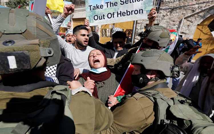 Seorang wanita Palestina menyerukan slogan di depan pasukan Israel saat memprotes pemukim Israel, di Hebron, wilayah pendudukan Israel Tepi Barat, Jumat (26/2/2021)