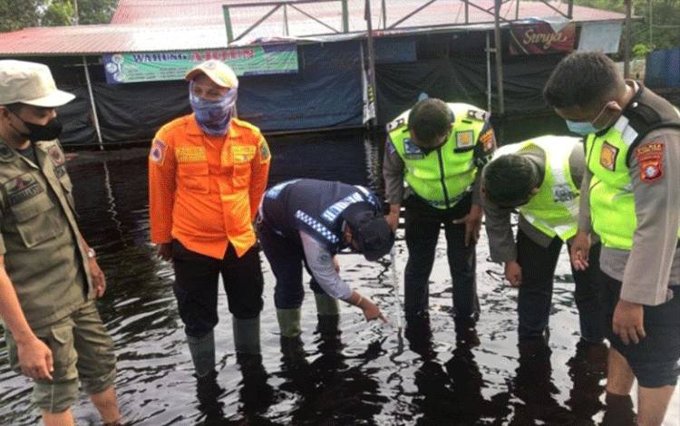 Para personel mengecek kondisi ketinggian air di Jalan Tumbang Nusa, Jumat, 26 November 2021 pukul 15:14 WIB.
