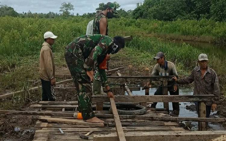 Warga bersama Anggota Koramil Kapuas Hilir memperbaiki jembatan di Desa Saka Batur Handil Humbang RT 06, Kecamatan Kapuas Hilir.
