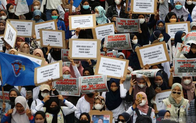Buruh membentangkan poster saat berunjuk rasa di Jalan Basuki Rahmat, Surabaya, Jawa Timur, Senin (29/11/2021). Mereka menuntut perbaikan Upah Minimum Provinsi (UMP). ANTARA FOTO/Didik Suhartono/rwa.