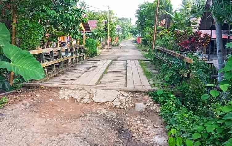 Bagian jalan yang ambles RT 38 Kelurahan Ampah Kota akibat dinding sayap jembatan jebol
