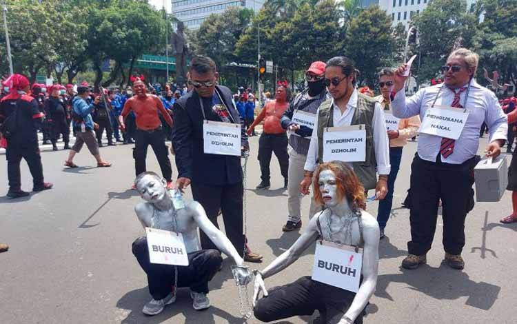 Aksi teatrikal yang menampilkan tokoh manusia silver dan pengusaha dalam aksi unjuk rasa gabungan di kawasan Bundaran Patung Kuda, Jakarta, Rabu (8/12/2021)