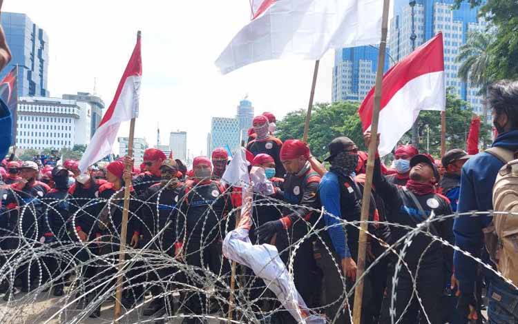 Ribuan buruh dari berbagai federasi mencoba menerobos barikade kawat berduri di Jalan Merdeka Barat, Jakarta Pusat, Rabu (8/7/2021).