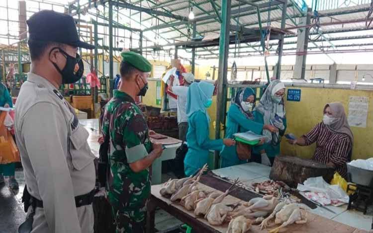 Babinsa Kelurahan Baru dan Bhabinkamtibmas mengawal petugas melakukan vaksin mobile di Pasar Indra Sari Pangkalan Bun