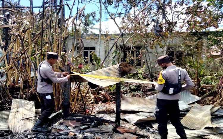 Anggota Polsek Gunung Purei memasang garis polisi di tempat kejadian perkara (TKP) musibah kebakaran di Desa Tambaba, Sabtu 11 Desember 2021