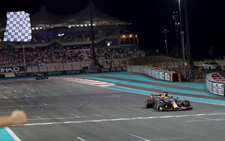 Pebalap tim Red Bull Max Verstappen melintasi garis finis untuk menjuarai Grand Prix Abu Dhabi di Sirkuit Yas Marina, Minggu (12/12/2021)