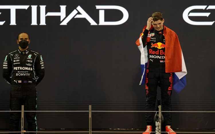 Pebalap tim Mercedes Lewis Hamilton berada di podium saat pebalap Red Bull Max Verstappen melakukan selebrasi setelah merebut gelar juara dunia F1 di Abu Dhabi, Sirkuit Yas Marina, UAE, MInggu (12/12/2021)