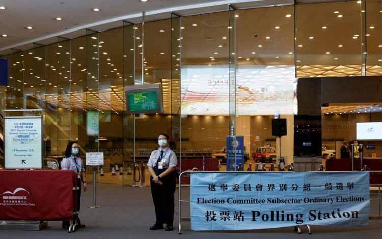  Petugas berjaga di luar tempat pemungutan suara dalam pemilihan anggota komite pemilu di Hong Kong, Minggu (19/11/2021)