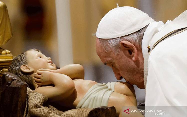 Paus Fransiskus mencium patung bayi Yesus saat ia merayakan Misa Kudus Malam Natal di Basilika Santo Petrus di Vatikan, Jumat (24/12/2021). REUTERS/Guglielmo Mangiapane/pras/sa. (REUTERS/GUGLIELMO MANGIAPANE)