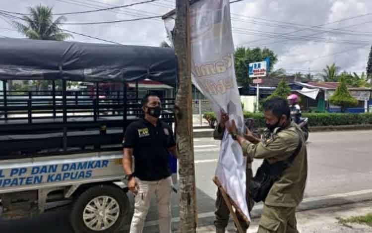 Personel Satpol PP dan Damkar Kapuas menertibkan spanduk di pinggir Jalan Kota Kuala Kapuas