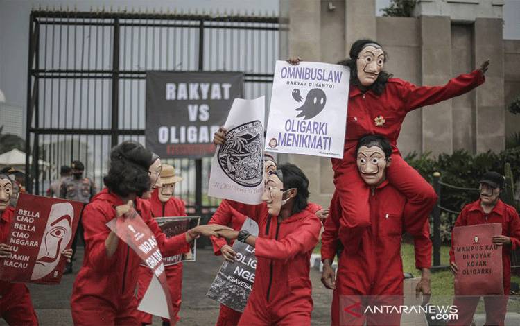 Aktivis yang tergabung dalam gerakan "People Heist" berunjuk rasa di depan Gedung DPR RI, Senayan, Jakarta, Senin (4/10/2021). Dalam aksi tersebut mereka mengajak publik untuk memperingati hari antioligarki nasional dengan momentum pengesahan 1 tahun UU Ciptaker oleh pemerintah dan parlemen. ANTARA FOTO/Dhemas Reviyanto/rwa.
