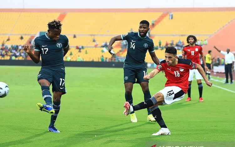 Bek tim nasional Mesir Ahmed Abou el Fotoh (kanan) menendang bola melewati hadangan penyerang Nigeria Samuel Chukwueze dalam laga penyisihan Grup D Piala Afrika 2021 di Stadion Roumde Adjia, Garoua, Kamerun, Selasa (11/1/2022) waktu setempat