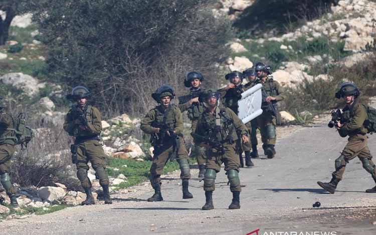 Tentara Israel bersiaga dengan senjata mereka dalam bentrokan dengan pengunjuk rasa Palestina di dekat Kota Nablus, Tepi Barat, Desember 2020