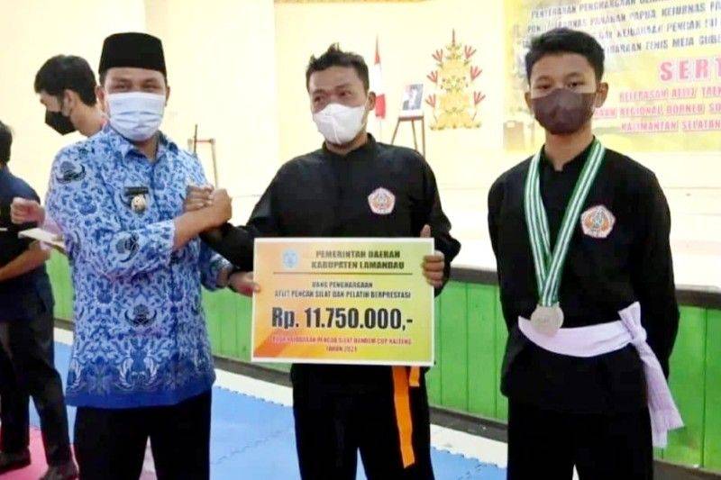 Bupati Lamandau Hendra Lesmana (kiri) menyerahkan uang pembinaan atlet dan pelatih berprestasi, Nanga Bulik, Senin, (17/1/2022)