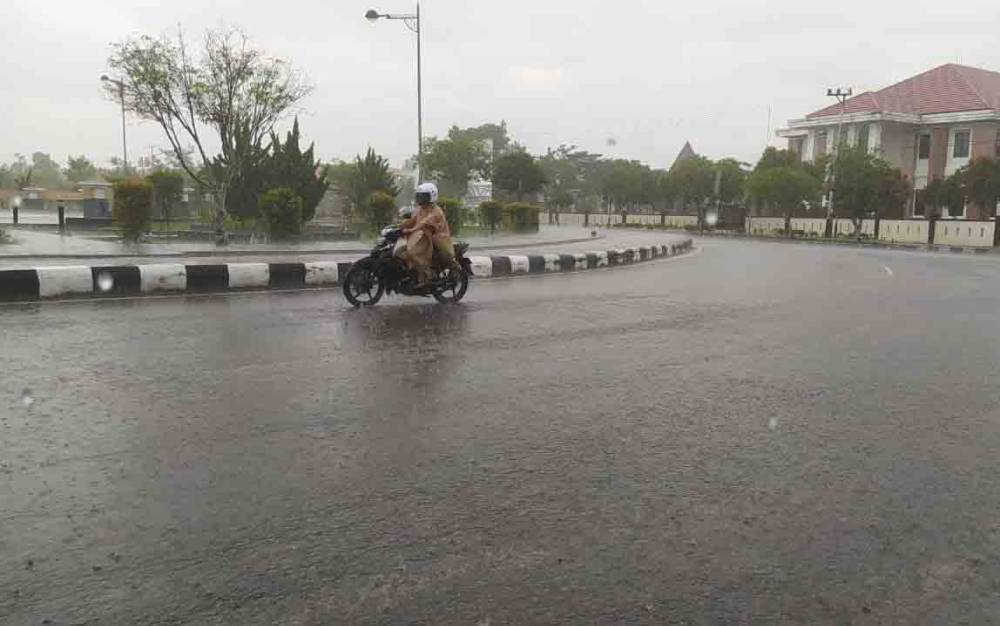 DOKUMENTASI - Salah seorang pengguna jalan melintasi terpaan hujan di Kota Palangka Raya  