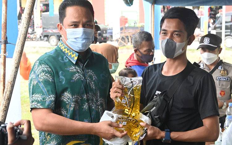  Bupati Hendra Lesmana memberikan minyakita ke pengunjung saat berada di stand pasar murah PT Citra Borneo Utama yang menjual MinyaKita dengan harga murah berkualitas tinggi, Jumat, 4 Februari 2022.