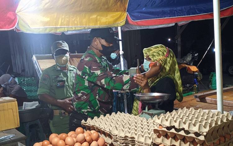 Anggota Babinsa Koramil 1016-01/Pahandut, Sertu Sunardi saat memberikan masker kepada salah satu pedagang di pasar malam tradisional dadakan jalan cilik riwut km 8 Palangka Raya.