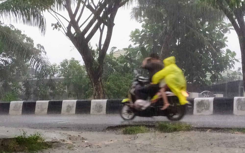 FOTO DOKUMEN - Pengendara motor melintasi jalan yang diguyur hujan di Sampit.