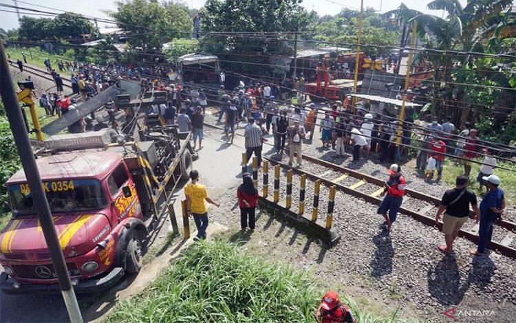 Suasana evakuasi bangkai bus pariwisata PO Harapan Jaya yang tertabrak KA Rapih Doho di perlintasan kereta api tanpa palang pintu di Desa Ketanon, Tulungagung, Jawa Timur, Minggu (27/2/2022). . ANTARA FOTO/Destyan Sujarwoko