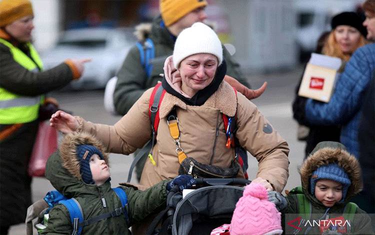 Warga Ukraina membawa anak-anaknya melintasi perbatasan di Siret, Rumania, Senin (28/2/2022). ANTARA FOTO/REUTERS/Stoyan Nenov/foc.