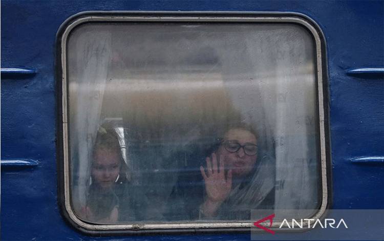 eorang wanita dan putrinya melihat keluar dari kereta evakuasi tujuan Lviv saat berpisah dengan suaminya di stasiun kereta pusat Kiev, Ukraina, Kamis (3/3/2022). (ANTARA/Reuters/Gleb Garanich/aww)