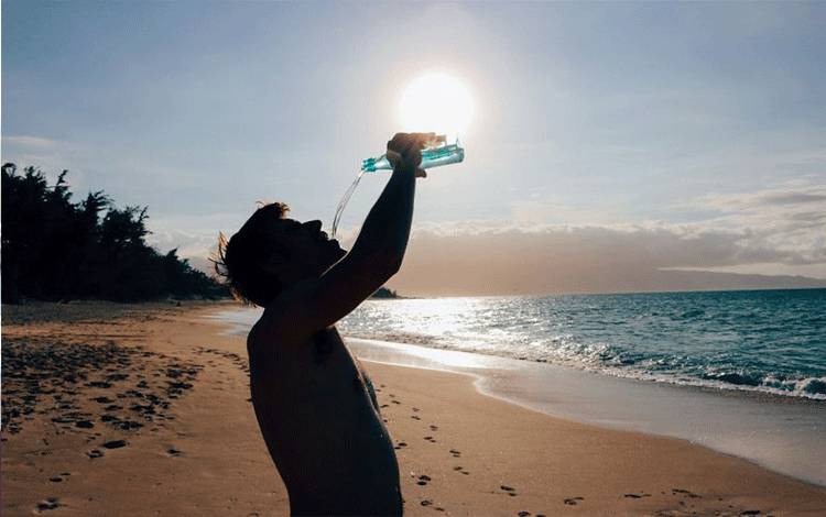 Ilustrasi seorang pria minum air di tengah hari yang panas. (Pixabay)