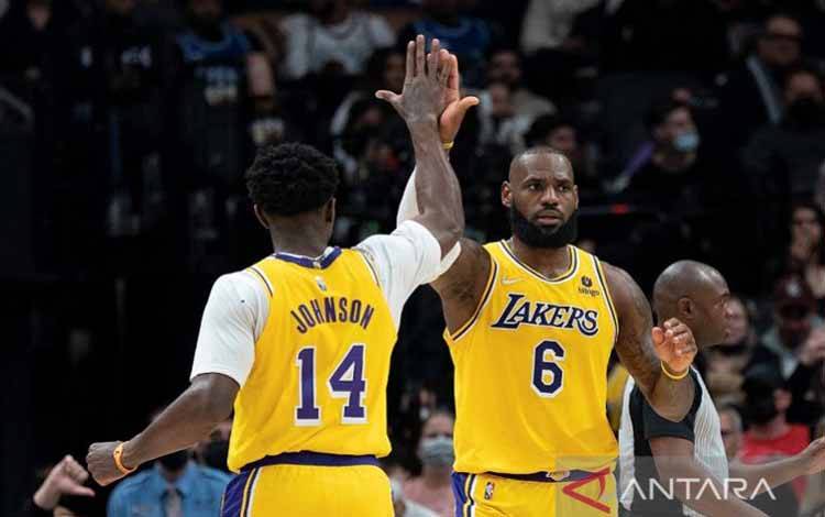 Megabintang Los Angeles Lakers LeBron James (kanan) dan Stanley Johnson melakukan tos berselebrasi atas raihan poin dalam pertandingan NBA melawan Toronto Raptors di Scotiabank Arena, Ontario, Kanada, Jumat (18/3/2022) waktu setempat